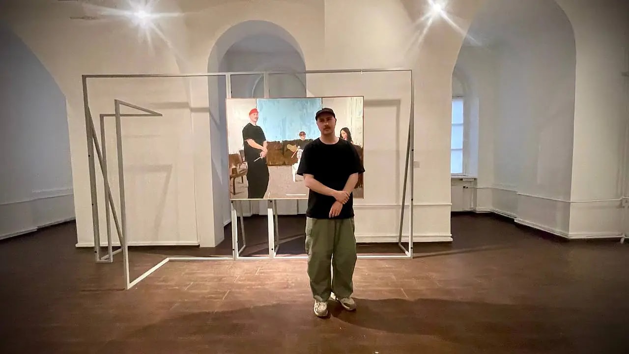 Художник Миша Никатин на фоне своей работы «Семейный портрет» (В ожидании)